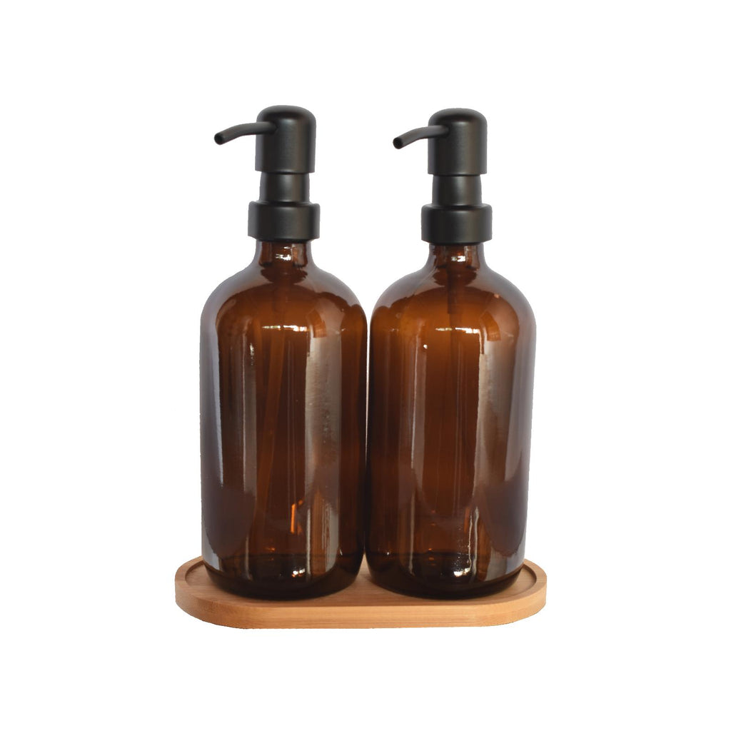 Amber glass bottle dispenser set with black pumps and bamboo tray