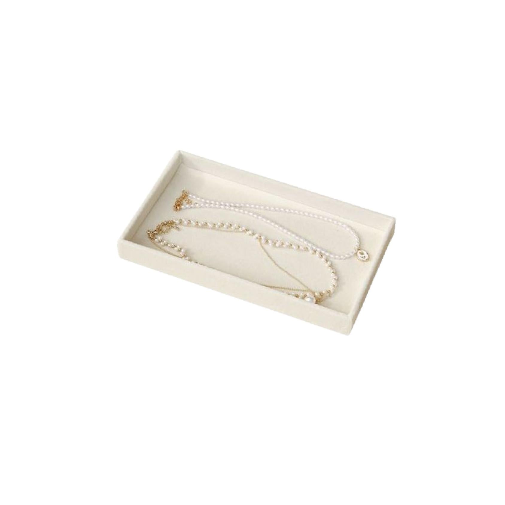 Two necklaces in a beige velvet rectangular open jewellery tray