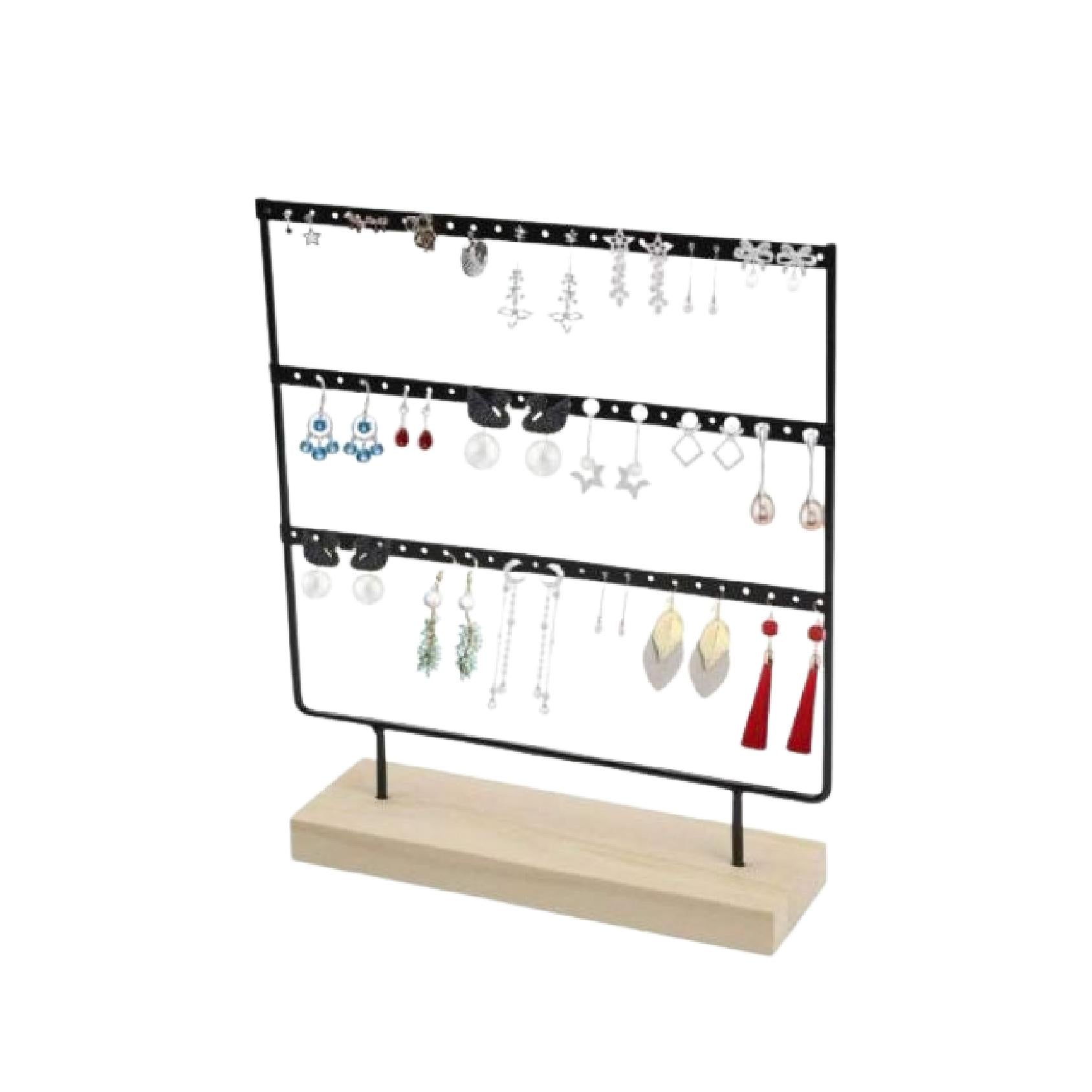 Black metal earring holder with three rows on a natural wood base displayed with assorted earrings.