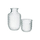 Clear embossed glass carafe and tumbler set on a white background