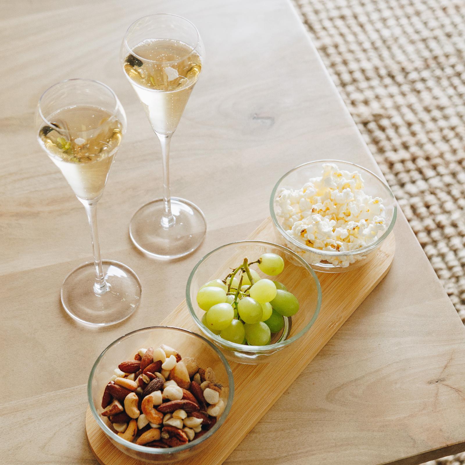 Nova champagne flutes styled on a table with fruit, nuts & popcorn for entertaining