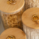 Close-up of gold handle & bamboo lid on ribbed glass jar filled with dry food