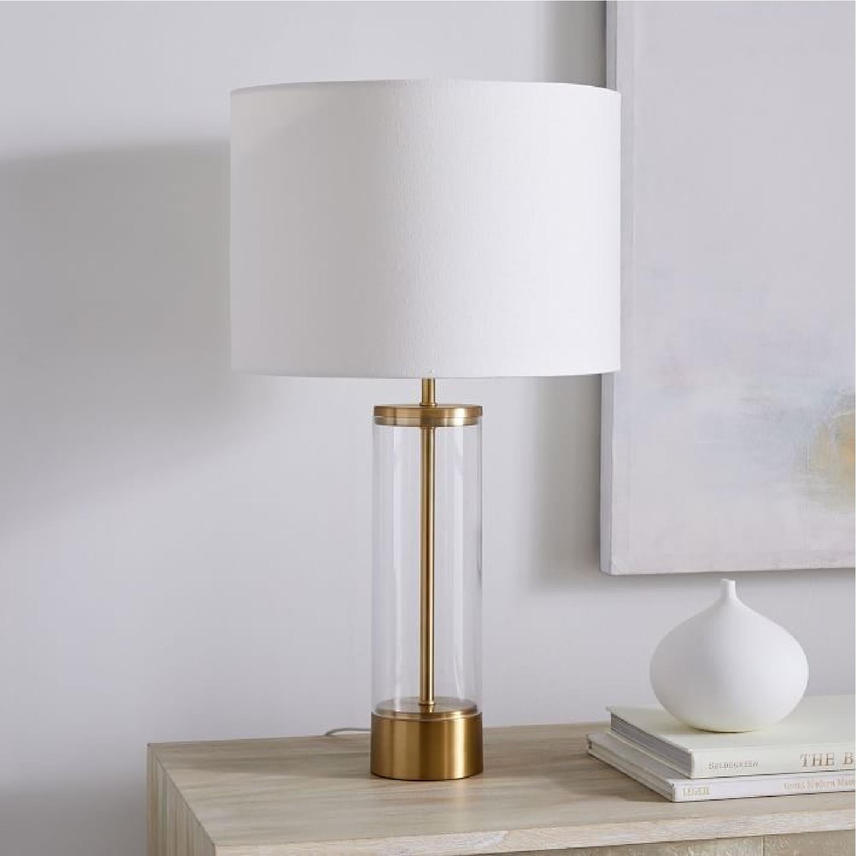 Table lamp with a white shade and a gold base styled on a sideboard