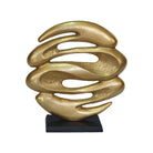 Gold abstract sculpture on a black base against a white background