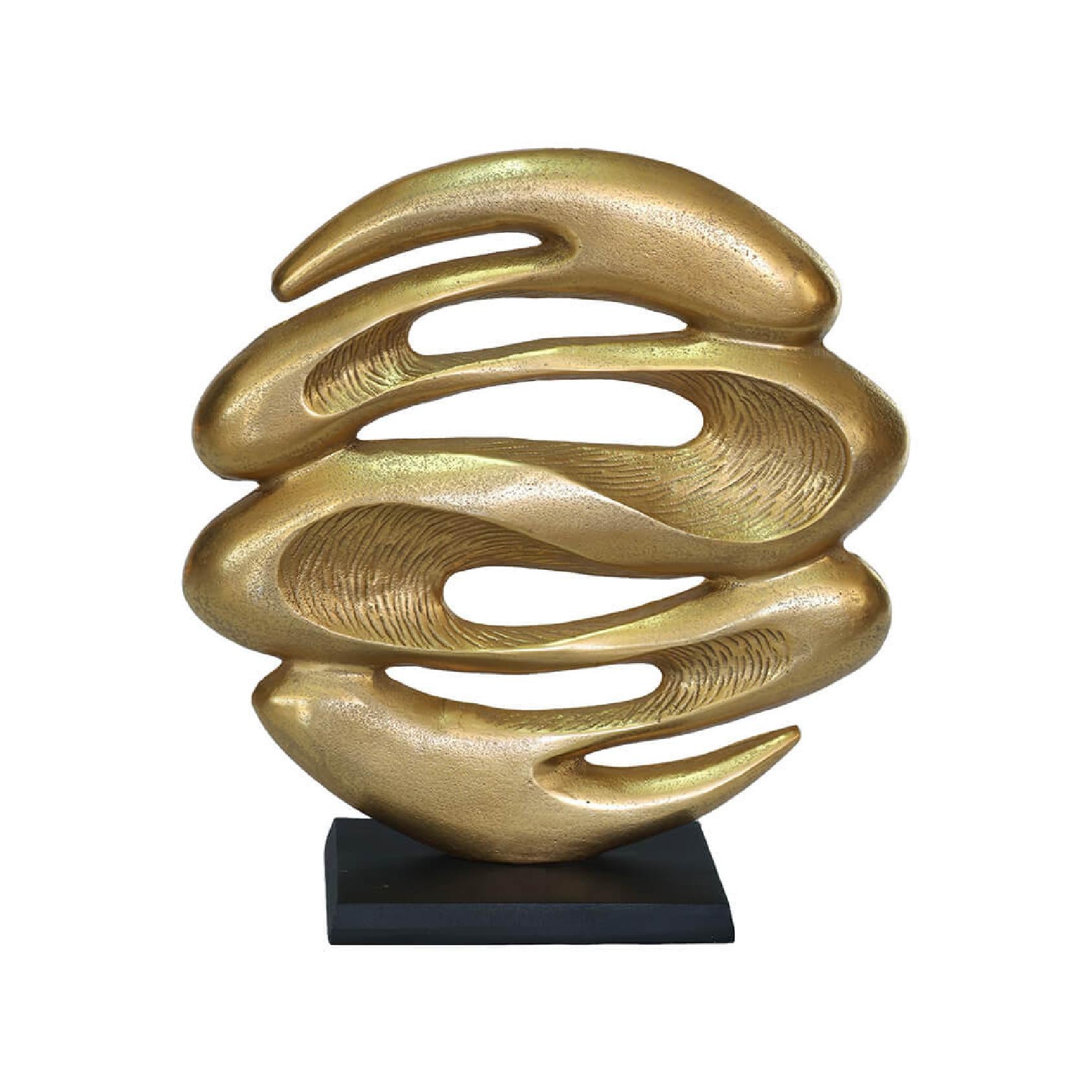 Gold abstract sculpture on a black base against a white background
