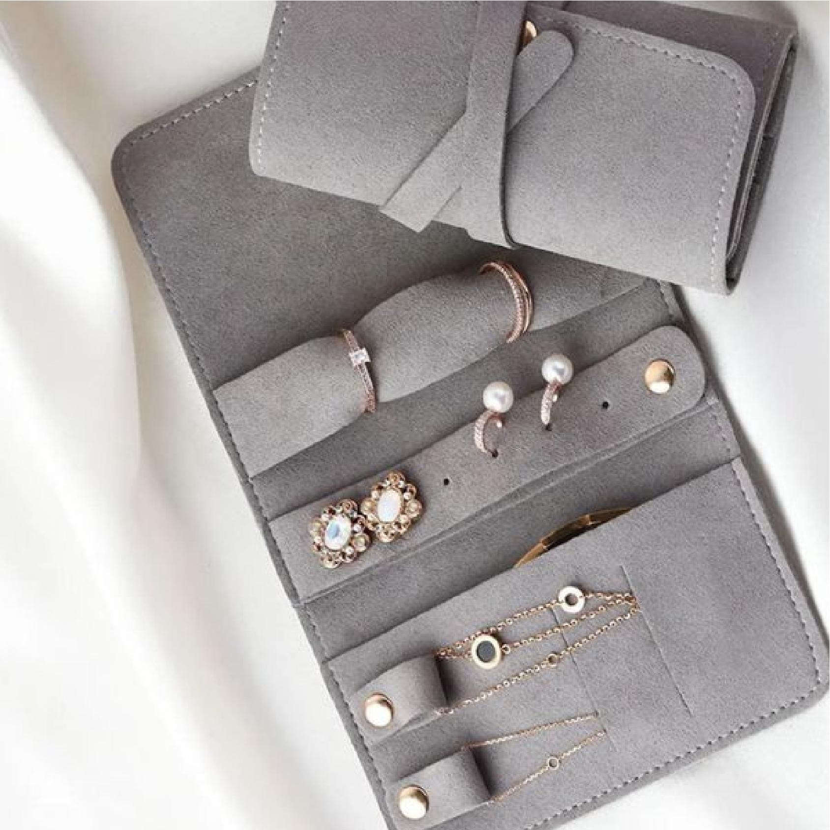 Close-up of grey jewellery roll interior with rings, earrings and studs