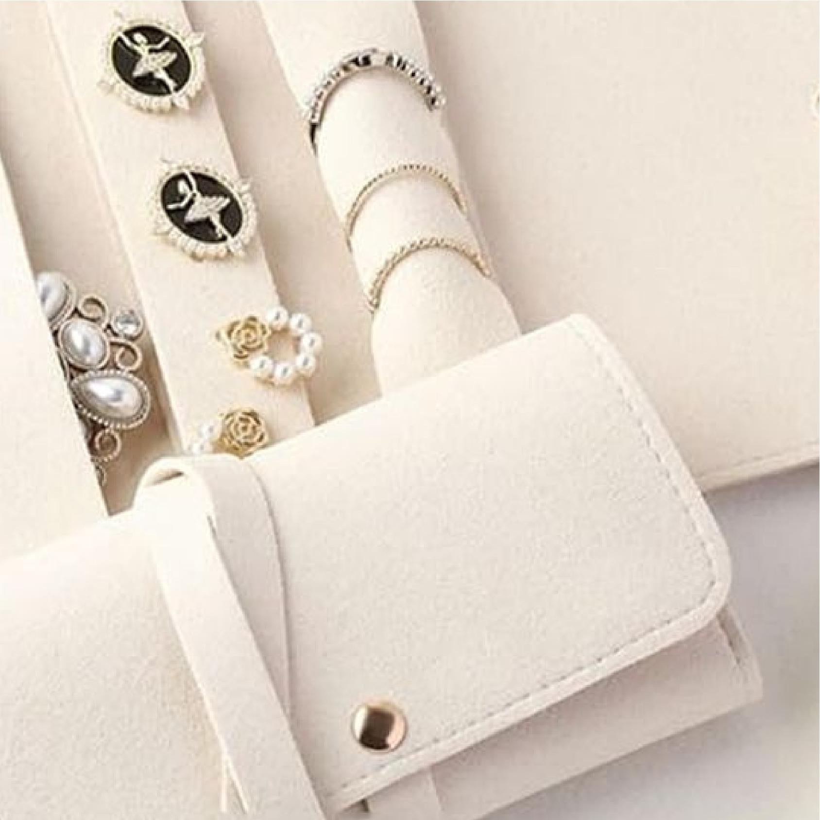 Close-up of ivory jewellery roll interior with rings, earrings and studs