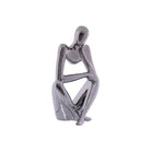 Silver metallic sculpture of a sitting figure