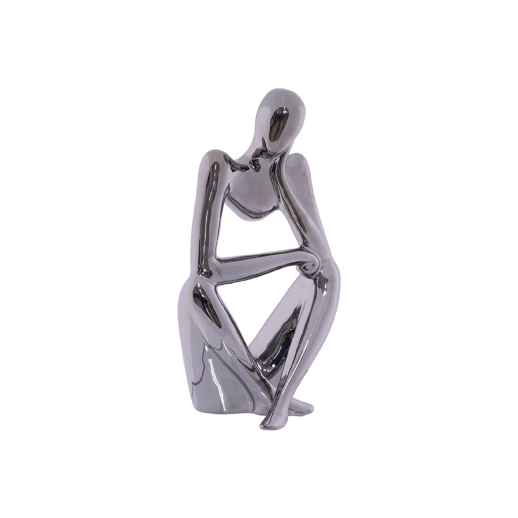 Silver metallic sculpture of a sitting figure