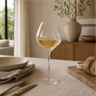 Clear wine glass with a slanted rim on a dining table