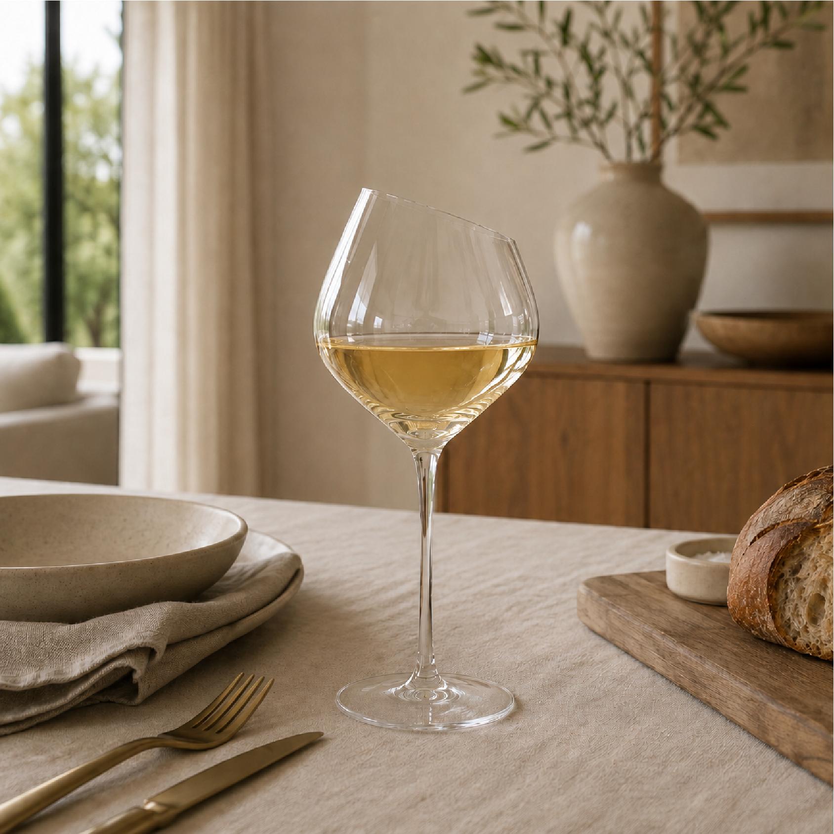 Clear wine glass with a slanted rim on a dining table