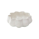 A white ceramic bowl with a scalloped, flower-like rim